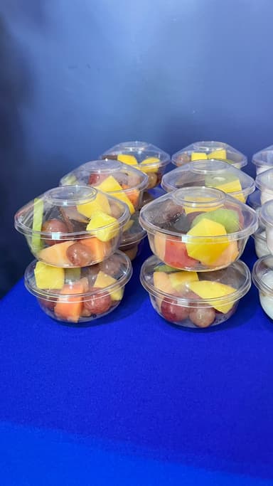 Rows of fresh fruit cups with mango and grapes